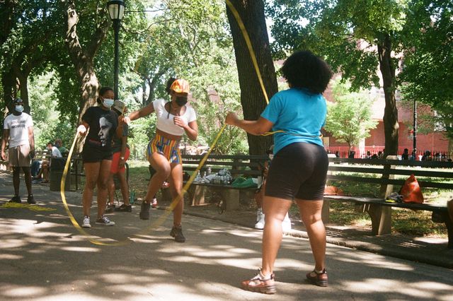 A young woman jumping rope between two other women.
